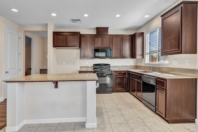 kitchen featuring light stone counters, a kitchen island, light tile patterned flooring, black appliances, and sink