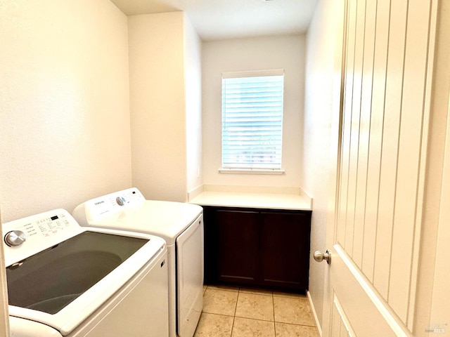 laundry area with cabinets, washing machine and dryer, and light tile patterned floors