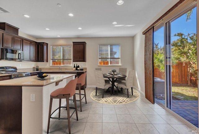 kitchen featuring gas range oven, black microwave, a wealth of natural light, and a kitchen breakfast bar