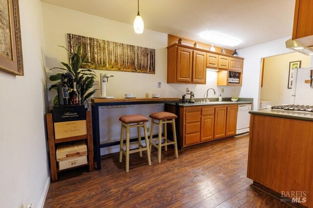 kitchen featuring a breakfast bar, sink, decorative light fixtures, dark hardwood / wood-style flooring, and white appliances