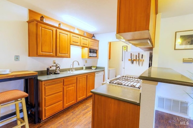 kitchen featuring dark hardwood / wood-style floors, sink, a breakfast bar area, and white appliances