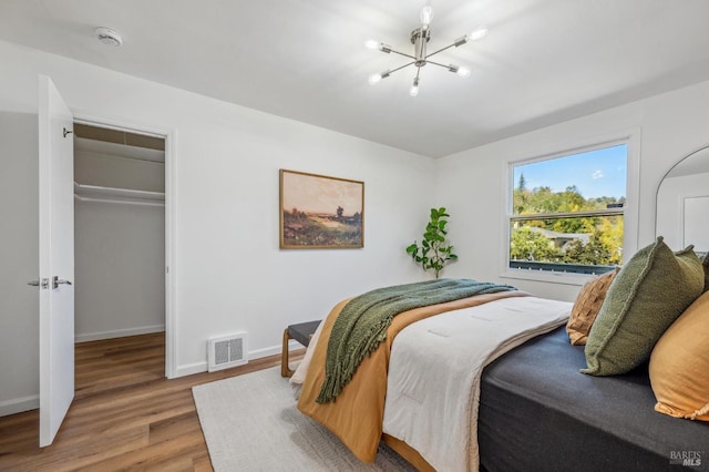 bedroom featuring an inviting chandelier, hardwood / wood-style floors, and a closet