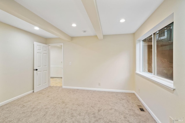 carpeted spare room featuring beamed ceiling