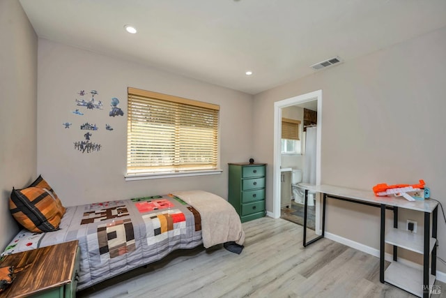 bedroom with connected bathroom and light wood-type flooring