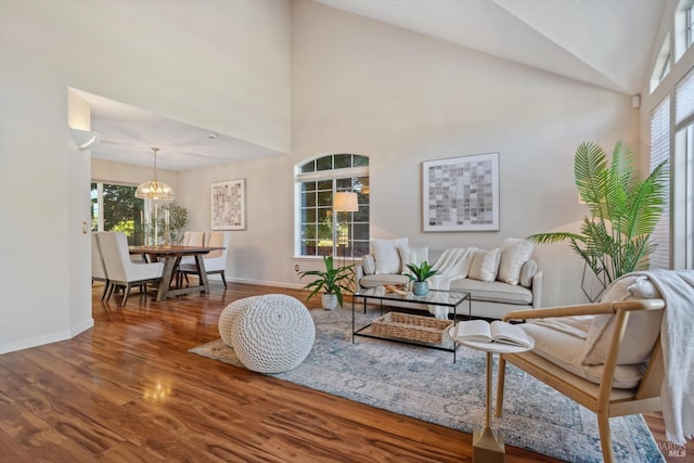 living room with high vaulted ceiling, hardwood / wood-style flooring, a wealth of natural light, and an inviting chandelier