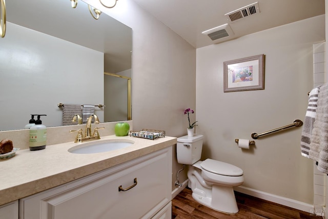 bathroom with hardwood / wood-style flooring, toilet, vanity, and walk in shower