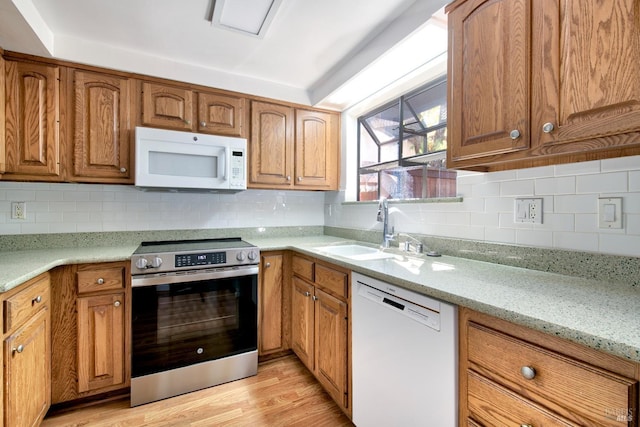 kitchen featuring light stone counters, sink, white appliances, and tasteful backsplash