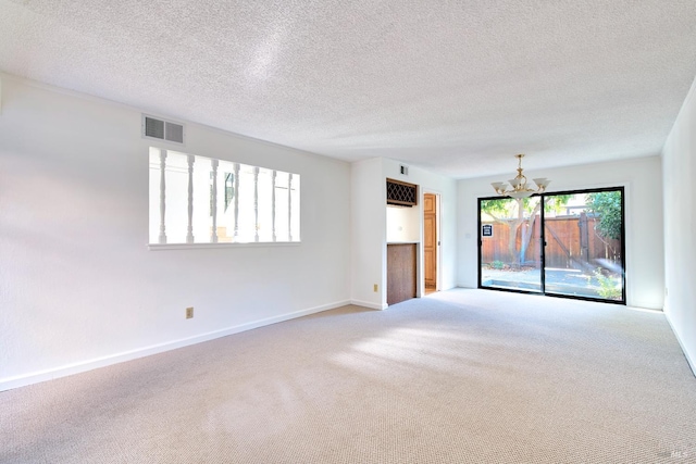 carpeted spare room featuring a textured ceiling and a notable chandelier