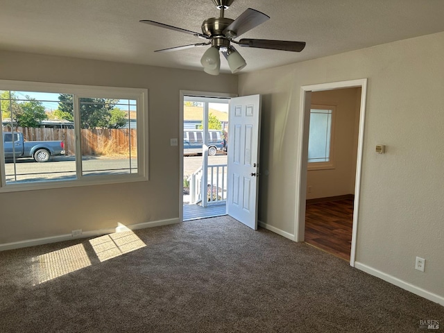 unfurnished room with ceiling fan and dark colored carpet