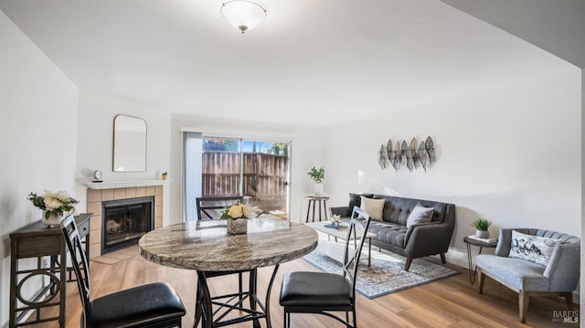 dining area featuring a fireplace, light wood-style floors, and baseboards