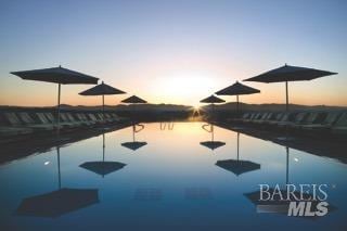 pool at dusk featuring a water view