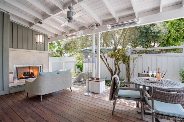 wooden deck featuring exterior fireplace and ceiling fan