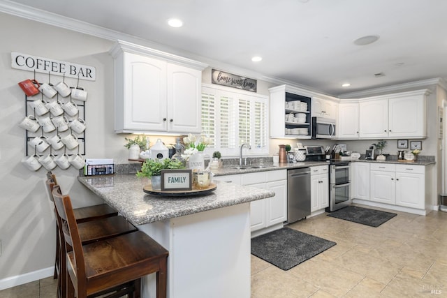 kitchen with crown molding, a peninsula, a kitchen bar, stainless steel appliances, and a sink