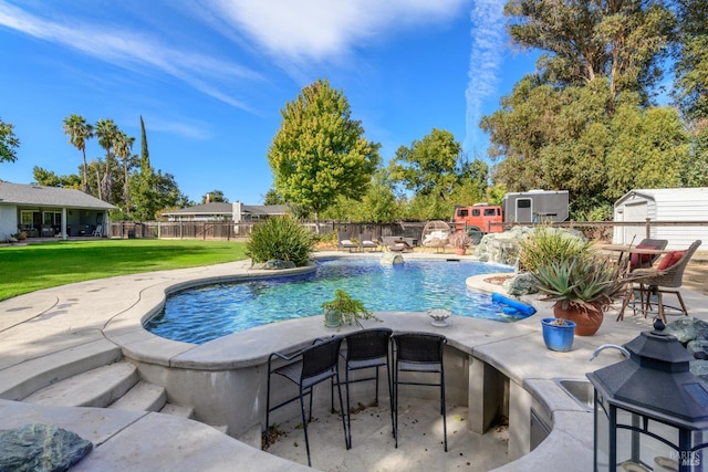 view of swimming pool with exterior bar, pool water feature, a shed, a yard, and a patio area