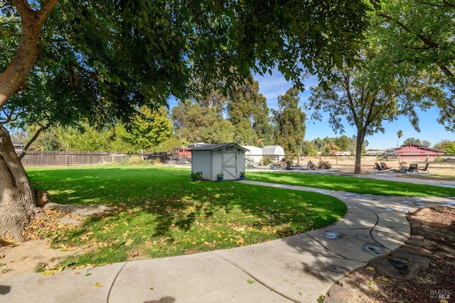 view of yard with a storage unit, fence, and an outdoor structure