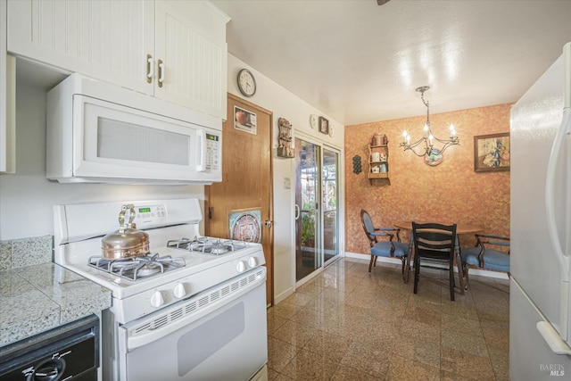 kitchen with a notable chandelier, white cabinets, pendant lighting, and white appliances