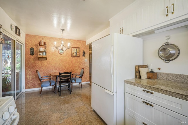 kitchen with hanging light fixtures, white refrigerator, stove, a chandelier, and white cabinetry