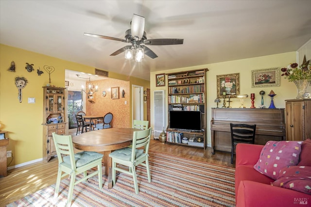 dining area with hardwood / wood-style flooring and ceiling fan with notable chandelier