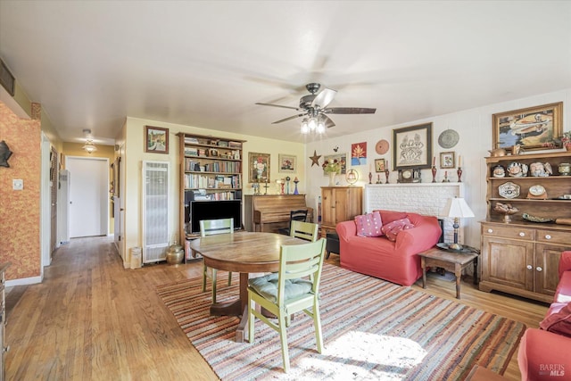 living room featuring light wood-type flooring, a brick fireplace, and ceiling fan