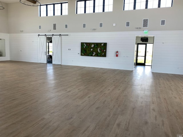 interior space featuring a towering ceiling, a wealth of natural light, and a barn door