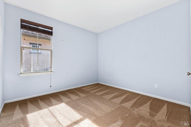 carpeted empty room featuring baseboards