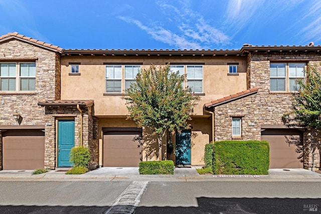 view of property featuring a garage, stucco siding, and stone siding
