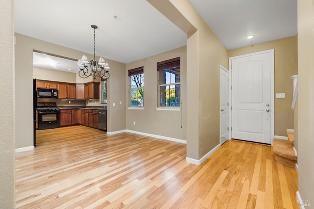 kitchen featuring black appliances, light hardwood / wood-style flooring, pendant lighting, and an inviting chandelier