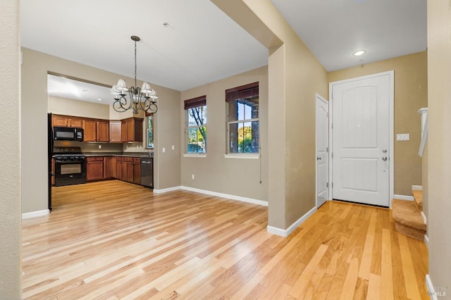 kitchen featuring black microwave, stainless steel dishwasher, light wood finished floors, an inviting chandelier, and gas range oven