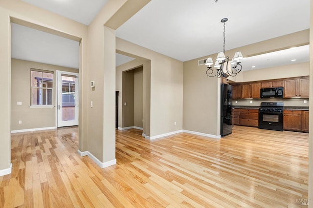 kitchen featuring visible vents, dark countertops, black appliances, light wood finished floors, and an inviting chandelier