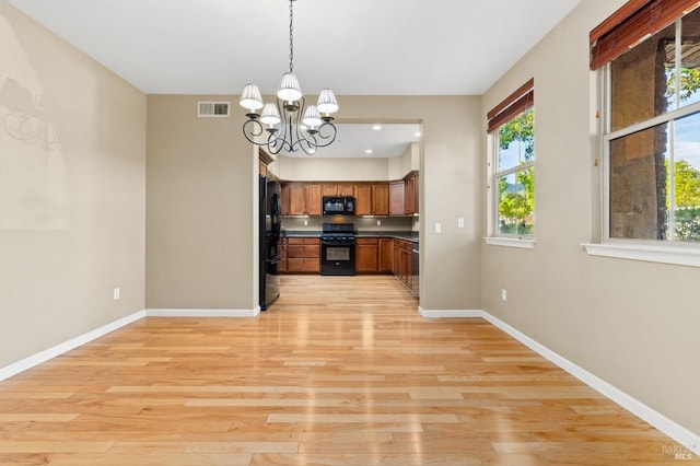 kitchen with an inviting chandelier, black appliances, light wood-type flooring, and pendant lighting