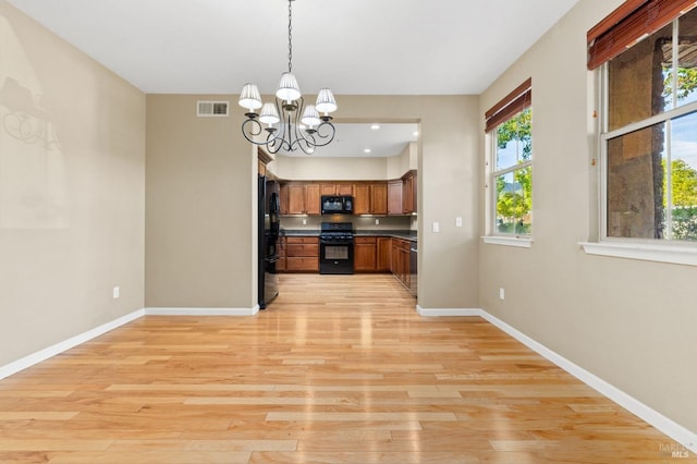 kitchen with light wood-type flooring, black appliances, brown cabinets, and visible vents