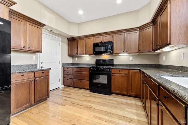 kitchen with visible vents, recessed lighting, light wood-type flooring, dark stone countertops, and black appliances
