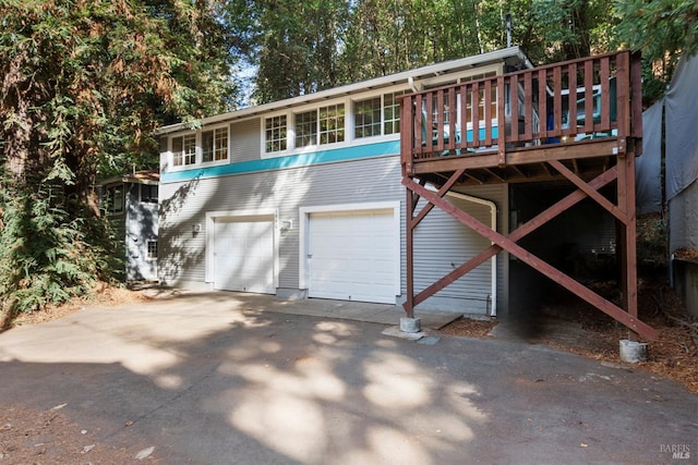 back of house featuring a garage, driveway, and a wooden deck