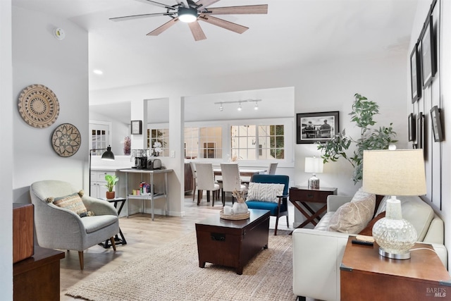 living area featuring light wood-style flooring, track lighting, and a ceiling fan