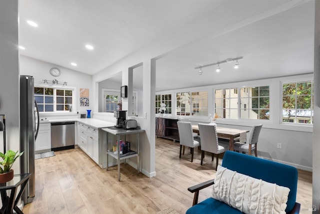 kitchen featuring vaulted ceiling, appliances with stainless steel finishes, light wood-type flooring, and white cabinetry