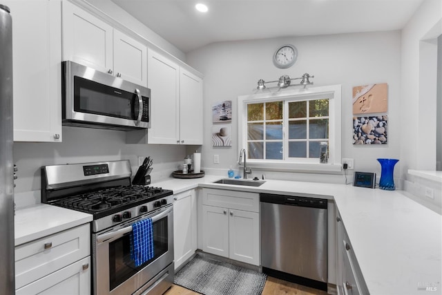 kitchen with white cabinetry, stainless steel appliances, a sink, and light countertops