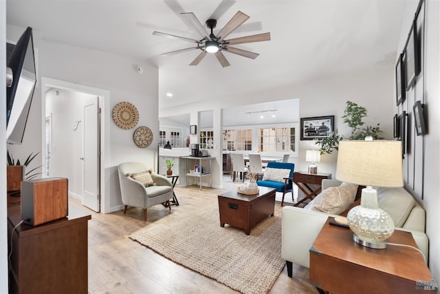 living room featuring vaulted ceiling, light wood-style flooring, and a ceiling fan