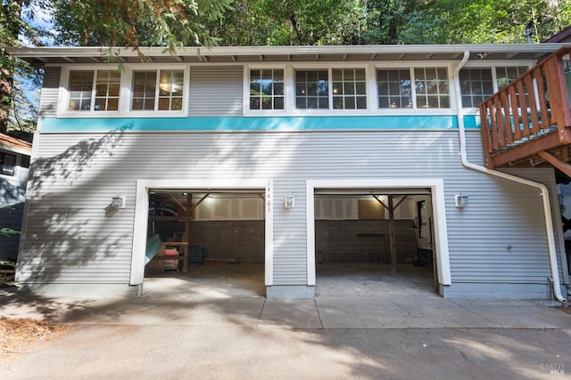 rear view of property featuring concrete driveway and an attached garage