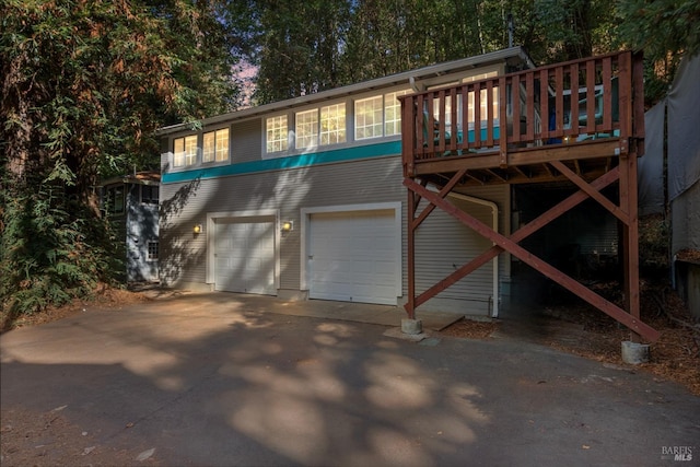 exterior space with driveway, a deck, and an attached garage