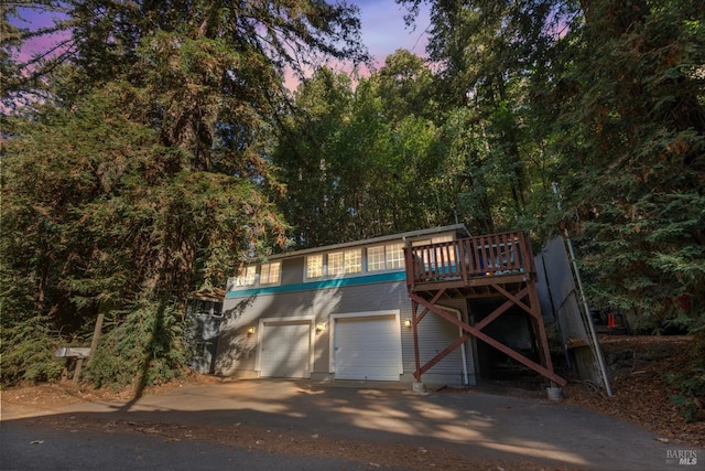 view of front of property featuring driveway, a deck, and an attached garage