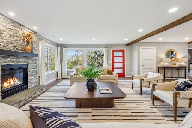 living room featuring beam ceiling, light wood-type flooring, and a stone fireplace