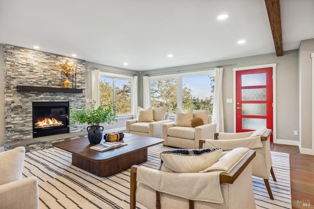 living room with a fireplace, beam ceiling, light hardwood / wood-style flooring, and a healthy amount of sunlight