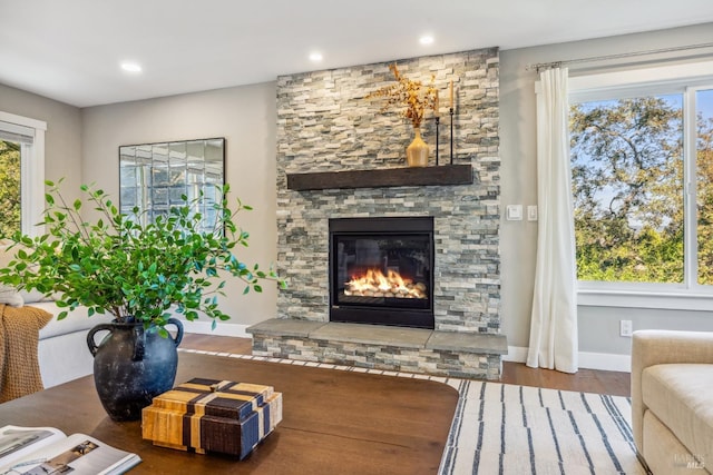 sitting room with a stone fireplace, plenty of natural light, and hardwood / wood-style flooring