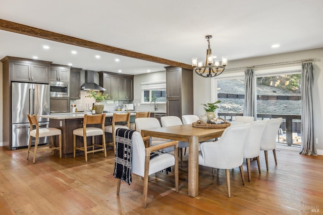 dining room with beam ceiling, a wealth of natural light, a notable chandelier, and light wood-type flooring