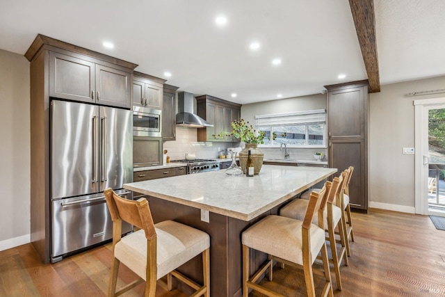 kitchen with a center island, wall chimney exhaust hood, dark hardwood / wood-style floors, appliances with stainless steel finishes, and beam ceiling