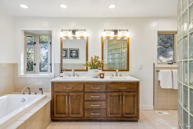 bathroom with tile patterned flooring, vanity, and a relaxing tiled tub