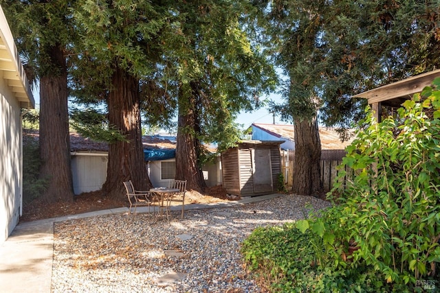 view of front facade featuring an outbuilding, a patio area, fence, and a storage shed