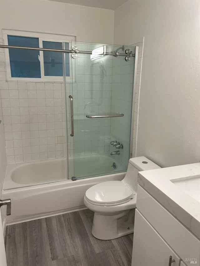 full bathroom featuring toilet, vanity, wood-type flooring, and shower / bath combination with glass door