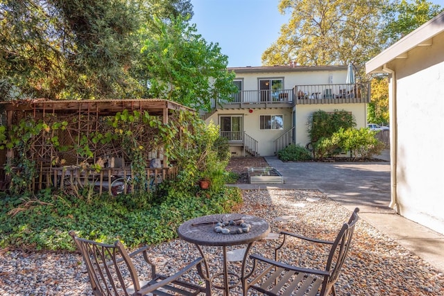 back of property with a balcony and stucco siding