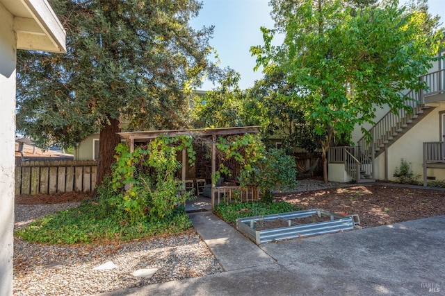 exterior space featuring stairs, fence, and a vegetable garden